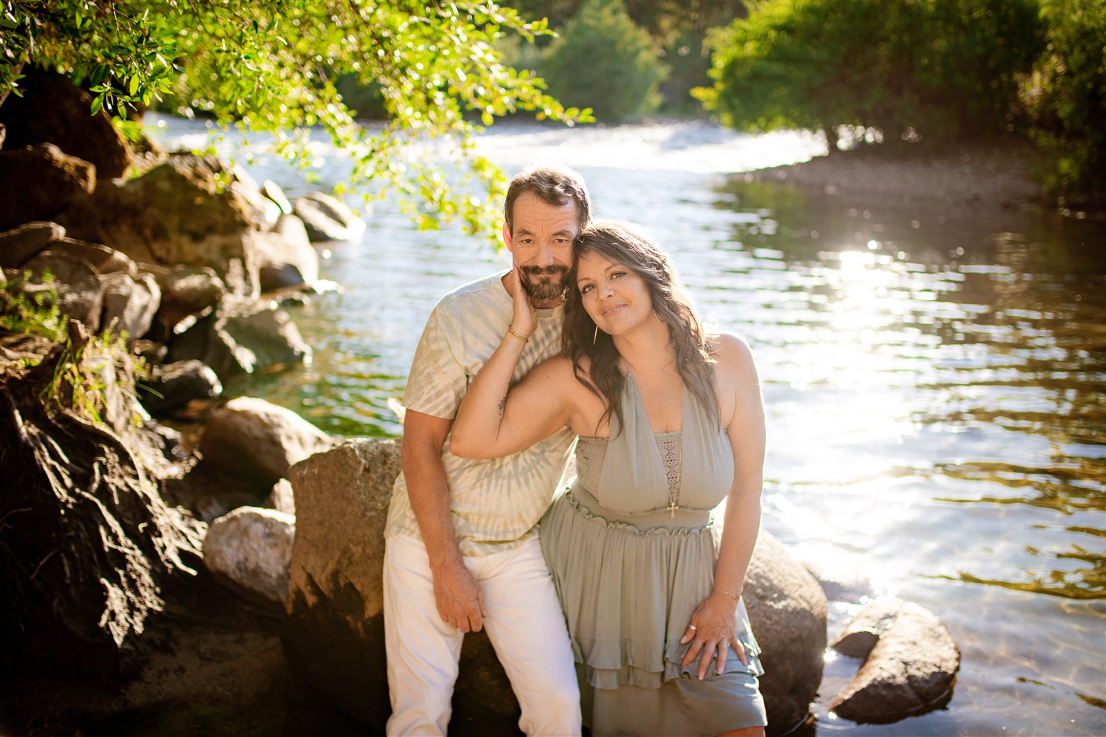 A couple smiling together beside a sunlit river